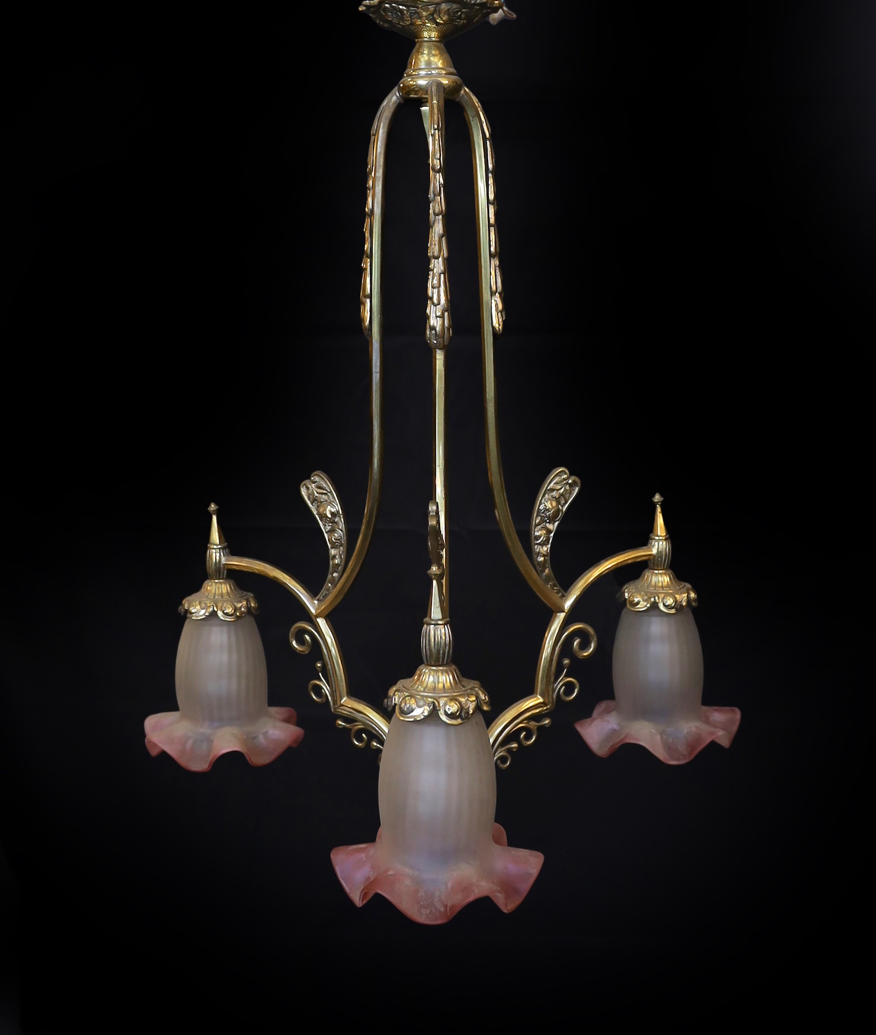 A 1930s French brass three light chandelier with cranberry tinted frosted glass shades, height 70cm. width 60cm